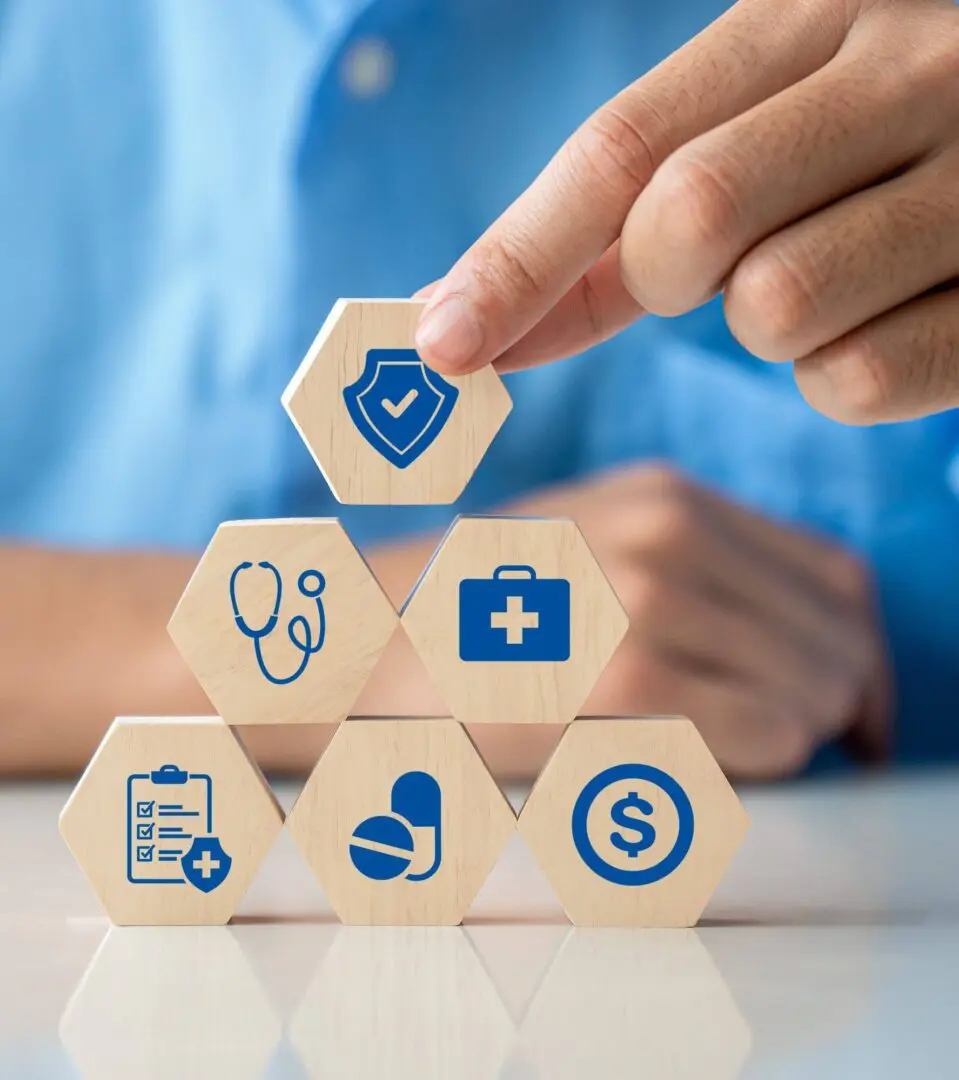 Stacked blocks with healthcare icons and hand.