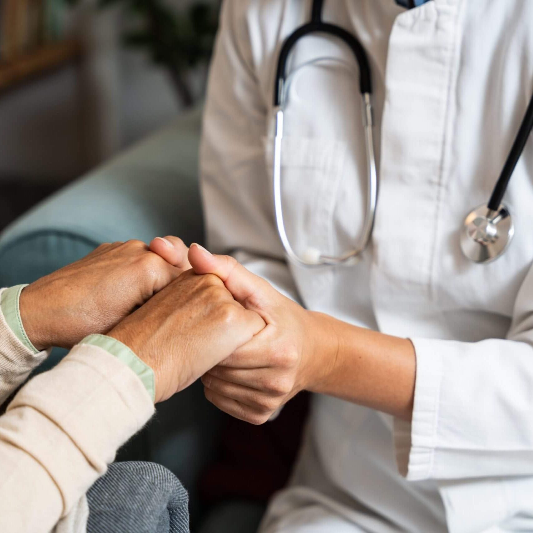 Doctor comforting patient, holding their hands.